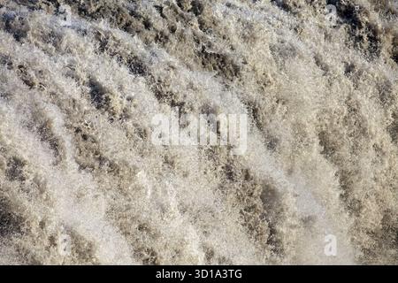 Blick auf das mächtige, aufgewühlte, schaumige Wildwasser, das über den Rand stürzt und eine dramatische und dynamische Szene schafft, Dettifoss, Nordurþing, Island. Stockfoto