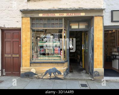 Der Blick auf den faszinierenden Buchladen „Murder and Mayhem“ lockt mit seinem dunklen Humor und Versprechen aufregender Lesungen, eingebettet im Herzen von Hay-on-Wye, Wale Stockfoto
