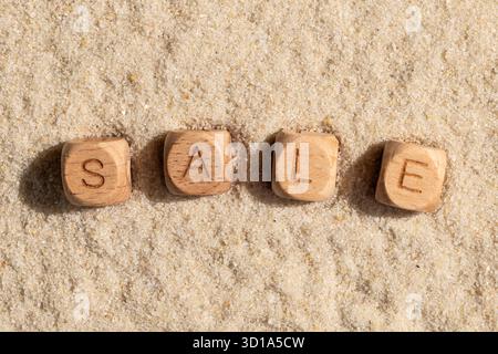 Holzblöcke, die Verkauf auf Sandstrand Hintergrund schreiben. Stockfoto