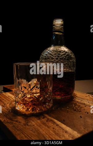 Amber Whiskey Flasche und Glas auf Holztisch – Moody Drink Stillleben Stockfoto