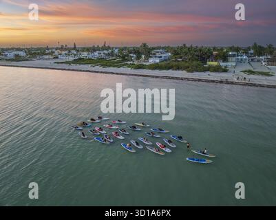 Aus der Vogelperspektive auf dem ruhigen türkisfarbenen Wasser in der Nähe des Sandufers unter einem lebendigen Sonnenuntergangshimmel, Progreso, Yucatan, Mexiko. Stockfoto