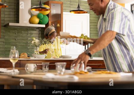 Essen in moderner Küche zubereiten, Seniorenpaar mit Wein und Gespräch. Kochen, kulinarisch, ältere Menschen, Begleitung || Model veröffentlicht Stockfoto