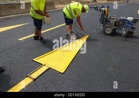 Bukarest, Rumänien - 20. Juni 2025: Arbeiter markieren mit gelber Farbe den Asphalt auf einer neu reparierten Straße. Stockfoto