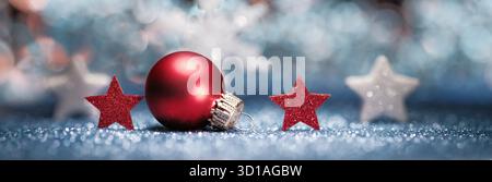 Rote und weiße Weihnachtsschmuck auf unscharfem blauem Hintergrund und glitzernder Oberfläche Stockfoto