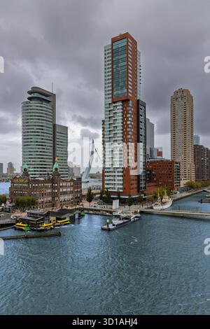 Eine vertikale Aufnahme der Skyline von Kop van Zuid mit modernen Wolkenkratzern, historischen Gebäuden: Dem Hotel New York und der Erasmus Bridge über die Nieuwe Maas Stockfoto