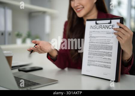 Erfahrene asiatische Erwachsene Immobilienmaklerin erklärt während der Beratung zum Hauskauf professionell wichtige Sachversicherungen Stockfoto