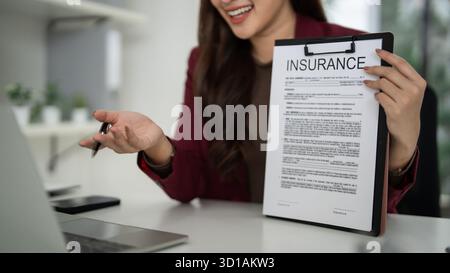 Erwachsene asiatische Verkaufsberaterin erklärt den Kunden Details zur Versicherungspolice. Professionelles Geschäftstreffen. Fachkundige Beratung von Immobilieninvestitionen. Stockfoto