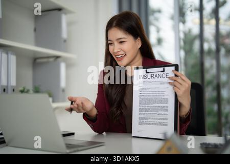 Asiatische Profi diskutiert Versicherungsdetails per Videokonferenz Sie erklärt Sachschutzpläne aus einer modernen Büroumgebung Connecti Stockfoto