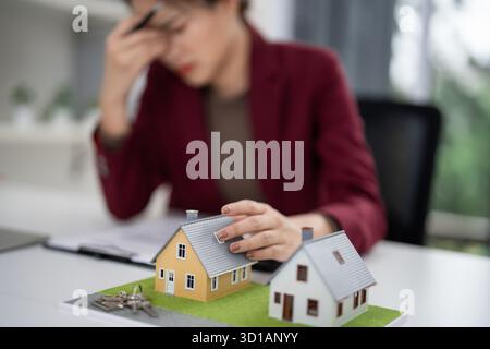 Professionelle Immobilienmakler fühlen sich unter Druck, wichtige Optionen für den Wohnungsmarkt zu erwägen. Schreibtisch zeigt Wohnmodelle und Schlüssel für Immobilien-pla Stockfoto