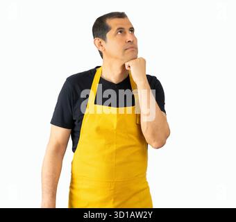 Verkäufer gutaussehender Mann, der die Schürze des Ladenbesitzers auf weißem isoliertem Hintergrund trägt, mit Hand am Kinn, der über Fragen nachdenkt, nachdenklicher Ausdruck. S Stockfoto