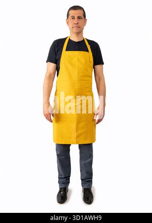 Aufnahme eines hispanischen Barista oder Kellners in voller Länge, der mit gelber Schürze vor weißem Hintergrund posiert Stockfoto