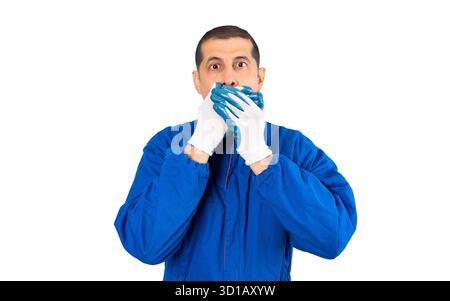 Schockierter Mechaniker, der seinen Mund mit isolierten Händen auf weißem Hintergrund bedeckt Stockfoto