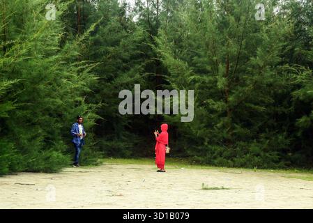 Zwei Leute in Einer Waldlichtung, eine Frau in Rot, die zusammen Fotos macht Stockfoto