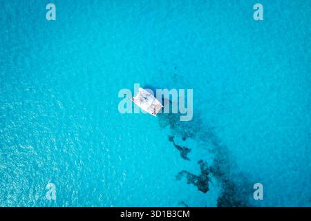 Aus der Vogelperspektive eines weißen Katamarans, der auf türkisfarbenem Wasser segelt, ein starker Kontrast zu den dunklen Schatten darunter, Cancun, Mexiko. Stockfoto