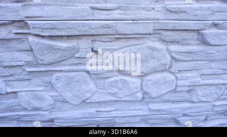 Ein Zaun oder eine Betonwand, natürliche Textur. Ivy klettert über die Betonoberfläche. Heller Hintergrund. Schatten. Stockfoto