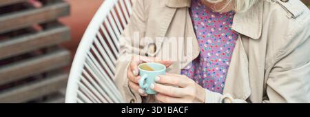 Reife weiße Frau genießt Kaffee im Freien in stilvoller Kleidung. Stockfoto