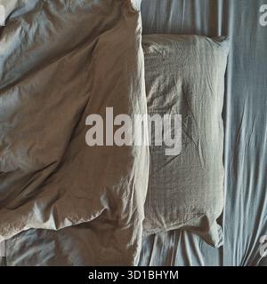 Graue Bettdecke mit Blick von oben, Bettdecke und Kissen im Bett. Stockfoto