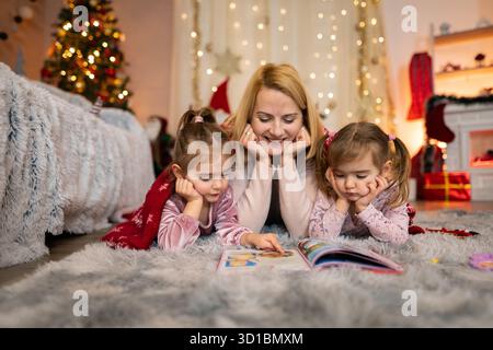 Mutter liest ihren beiden Töchtern eine Weihnachtsgeschichte vor Stockfoto