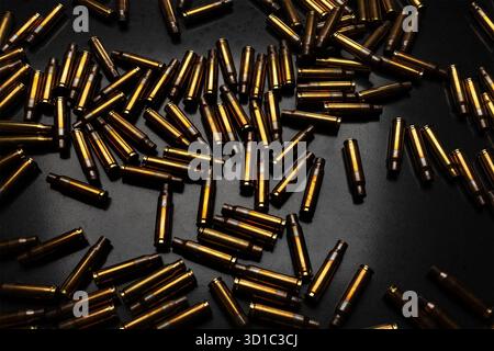 Verstreute Messingkugeln auf dunklem, reflektierendem schwarzem Hintergrund. Stockfoto