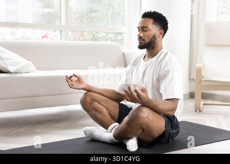 Stiller afrikanischer Mann in Sportkleidung, der Meditationspraxis macht Stockfoto
