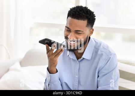 Junger afrikanischer Mann lächelt, während er mit der Freisprecheinrichtung spricht Stockfoto
