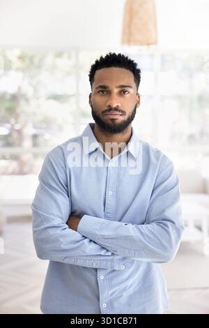 Vertikales Portrait schöner selbstbewusster afrikanischer Mann, der im Wohnzimmer steht Stockfoto