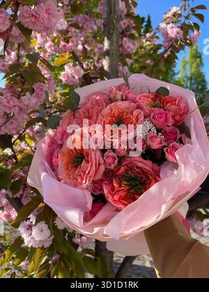 Dieses lebendige Bild fängt einen wunderschönen Blumenstrauß vor dem Hintergrund rosa Kirschblüten ein und macht es perfekt für Themen der Romantik und des Frühlings Stockfoto