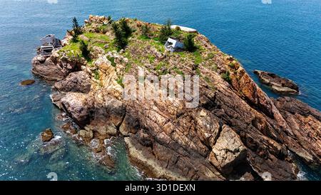 Felsige Insel in der Nähe von Quy Nhon, Vietnam – abgeschiedener Felsvorsprung mit Fischerhütten, türkisfarbenem Meer, rauer Natur und Küstenabenteuer, aus der Vogelperspektive Stockfoto