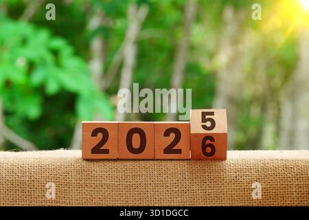 Holzblöcke im Wechsel von 2025 bis 2026. Silvester-Countdown und Neuanfang-Konzept vor Naturhintergrund. Stockfoto