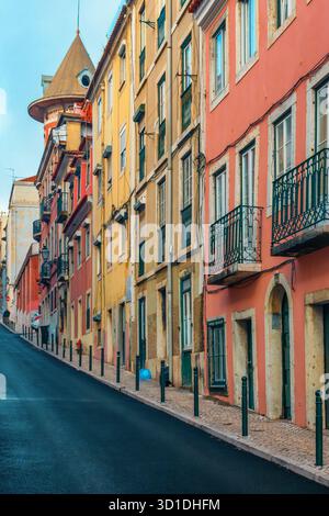 Farbenfrohe historische Gebäude mit schmiedeeisernen Balkonen an der steilen Straße in Lissabon, Portugal. Stadtstraße in der Altstadt von Lisboa. Vertikal Stockfoto