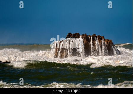 Mächtige Ozeanwellen schwellen und krachen gegen eine Felsformation an der Küste von Essaouira. Stockfoto