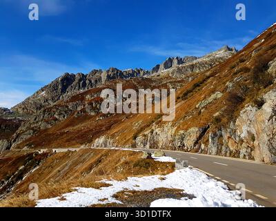 Eine atemberaubende Bergpassszene auf dem Sustenpass in der Schweiz mit schroffen Gipfeln, Passstraßen und goldenen Wiesen im späten Herbst Stockfoto