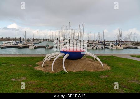 Große rote und blaue Krabbenskulptur auf Gras am Yachthafen mit Booten Stockfoto