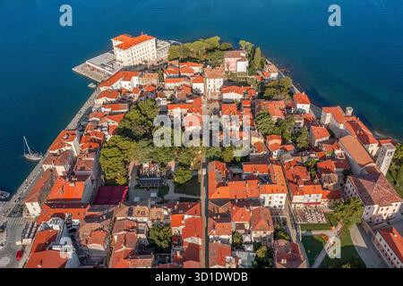 Aus der Vogelperspektive der leuchtenden orangefarbenen Dächer kaskadieren Richtung azurblauem Meer, umgeben von der historischen Architektur der Altstadt, Poreč, Istrien County, Croati Stockfoto