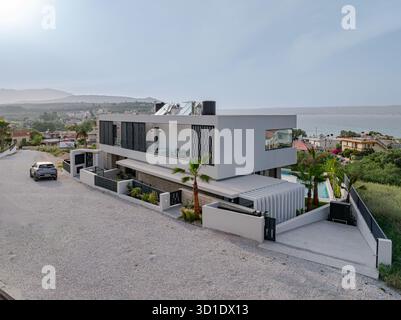 Blick aus der Vogelperspektive auf eine moderne Villa, die stolz vor dem Hintergrund des ruhigen Meeres und der fernen Hügel steht, Kalyves, Chania, Griechenland. Stockfoto