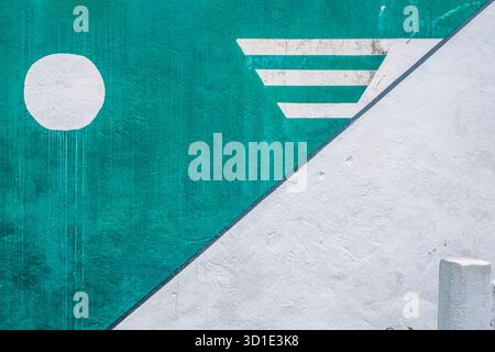 Modernes abstraktes geometrisches Wandgemälde mit einem strukturierten Bereich in Teal, weißen Formen und einer starken diagonalen Trennlinie Stockfoto