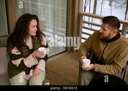 Junge kaukasische Frau und Mann trinken heiße Getränke draußen Stockfoto