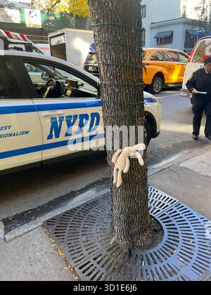 Verlorenes Kinderspielzeug-Kaninchen, das an einem Baum befestigt ist und vom NYPD auf der Third Avenue, Mid Town Manhattan, New York, USA gerettet wird Stockfoto