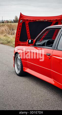 Rotes Auto aus den 1980er Jahren mit geöffneter Motorhaube. Seitenansicht des BMW M3 hinten – Performance-Version des deutschen Sportcoupés. Stockfoto