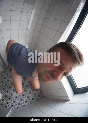 Mann, der auf der Toilette sitzt und an Magenschmerzen und Verdauungsstörungen leidet. Anzeichen einer Lebensmittelvergiftung Stockfoto