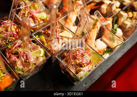 Aus nächster Nähe sehen Sie elegante Vorspeisetassen mit Meeresfrüchten, Limette und Sprossen auf einem Serviertisch. Stockfoto