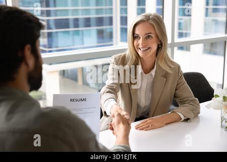 Glückliche blonde junge Bewerberin, die eingestellt wird Stockfoto