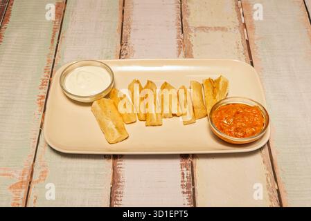 Hausgemachte gebratene Yuca mit knuspriger Kruste und zartem Zentrum, bestreut mit Knoblauchsalz und frisch gehackter Petersilie Stockfoto