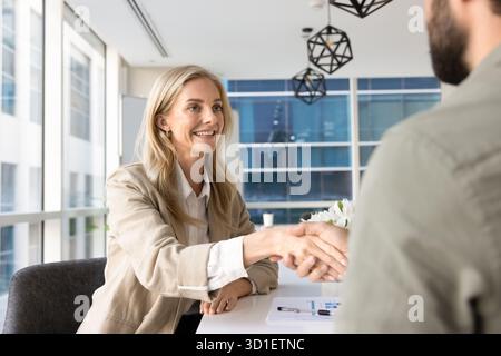Positive blonde junge Geschäftsfrau, die sich mit männlichem Geschäftspartner verständigt Stockfoto