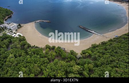 Aus der Vogelperspektive auf eine ruhige Bucht mit einem Sandstrand, umgeben von üppig grünen Wäldern. Aus der Vogelperspektive auf den wunderschönen Perla Strand in der Nähe von Primorsko, Bulgarien Stockfoto