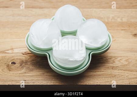 4 große runde Eiswürfelkugeln in einer grünen Silikonform zu Hause in Innenräumen. Stockfoto