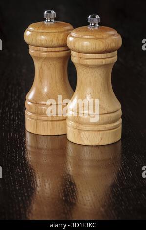 Zwei hölzerne Pfeffermühlen auf dunkler Tischoberfläche Stockfoto
