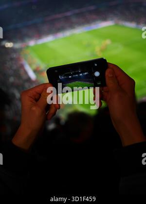 Die Person hält ein Handy und macht ein Foto von einem Fußballfeld Stockfoto