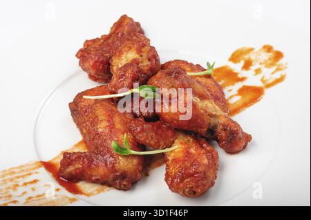 Gebratene Hähnchenschenkel in roter, scharfer Karamellsauce mit grünen Bohnensprossen auf weißem Teller Stockfoto