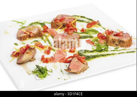 Kalbsfleischmedaillons mit Pesto-Sauce, Gemüse und Algen auf weißem Teller Stockfoto